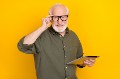 Portrait of candid friendly aged person hand touch eyewear look camera isolated on yellow color background.